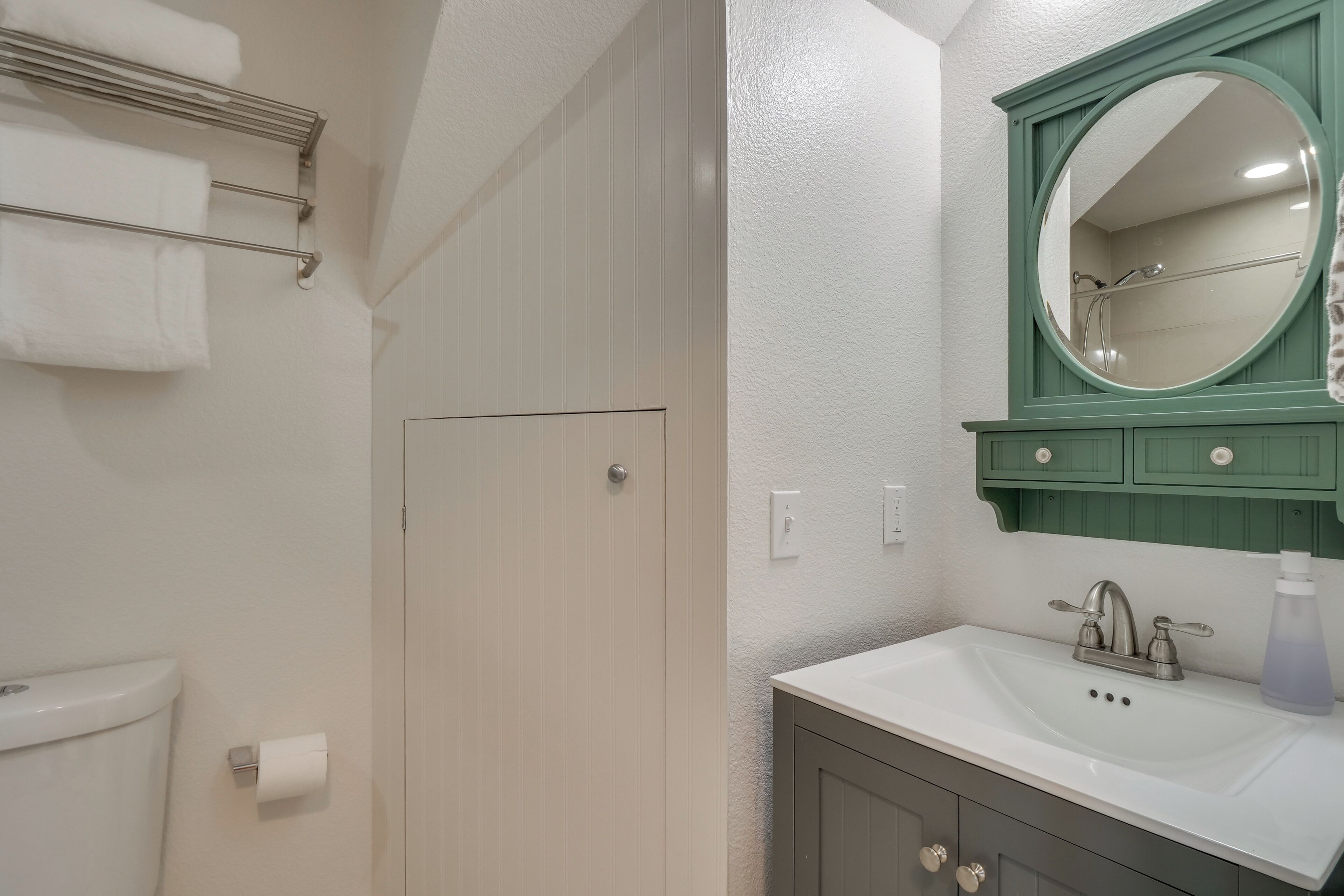 A bathroom with a toilet, a sink with a mirror, and a towel rack.