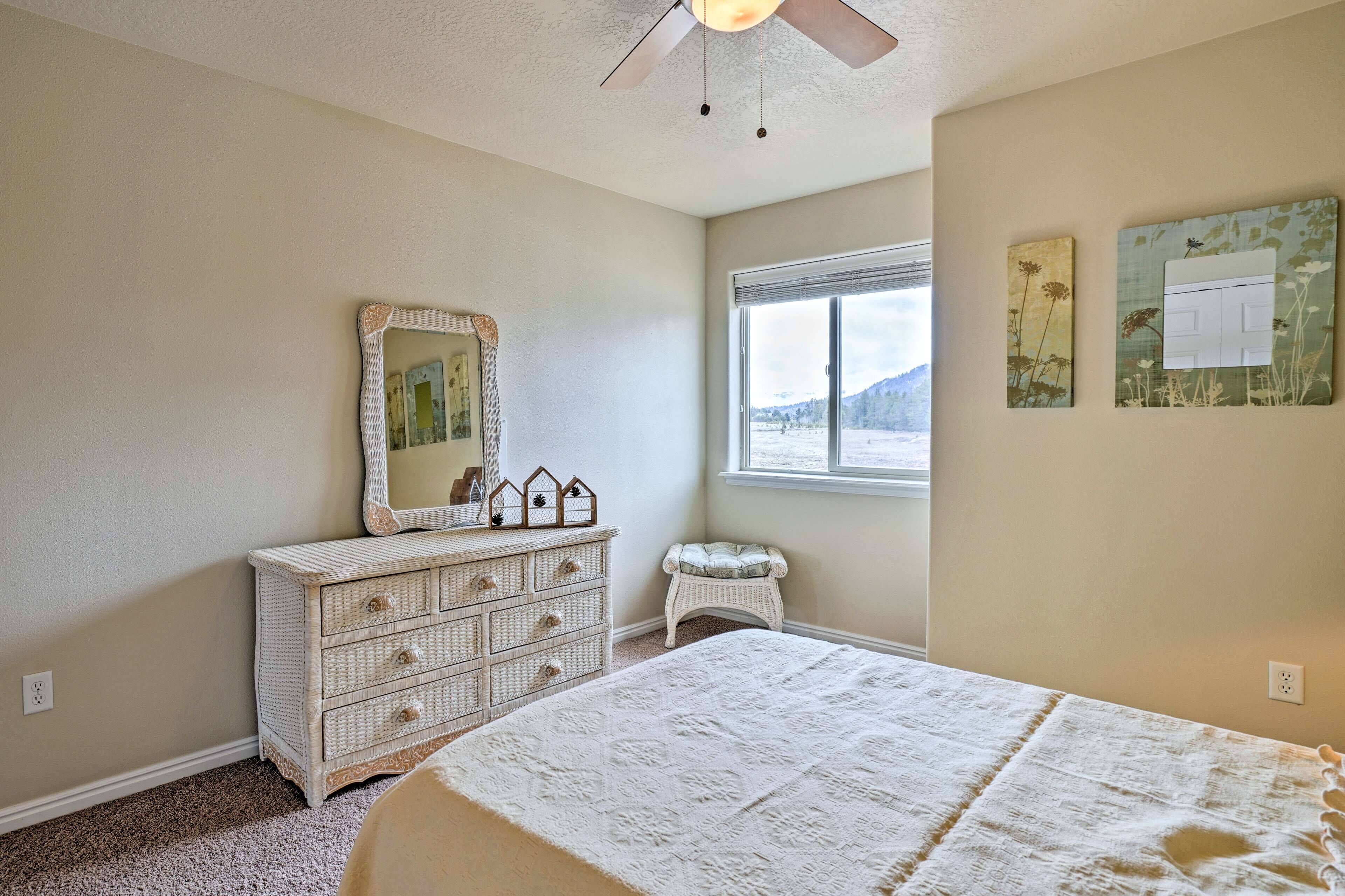 A bedroom with a bed, dresser, mirror, and window.