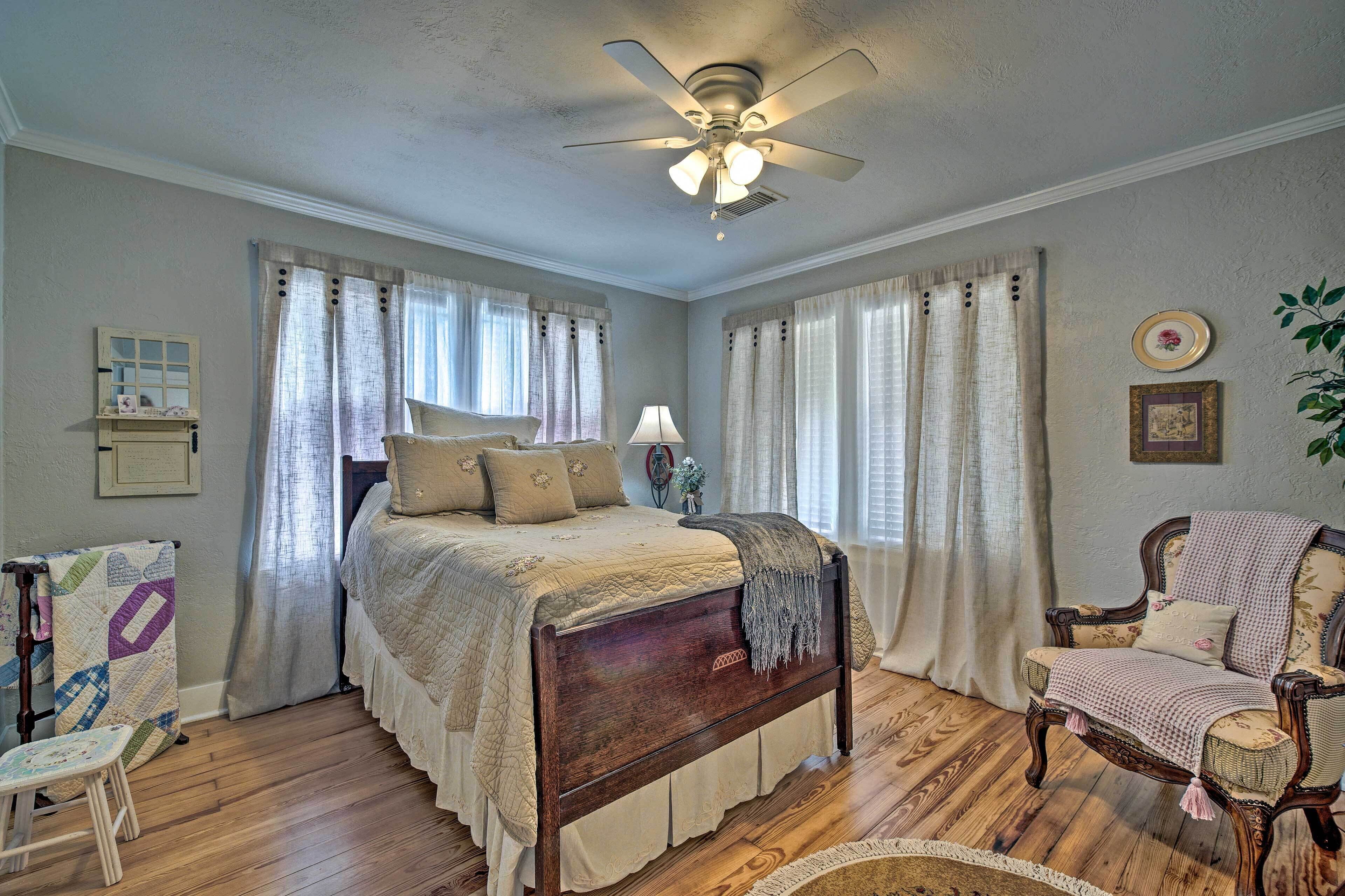 A bedroom with a wooden bed, a chair, a desk, and a ceiling fan.