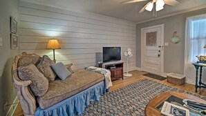 Ein Wohnzimmer mit einer Couch, einem Fernseher, einem Ventilator und Deckenventilator.