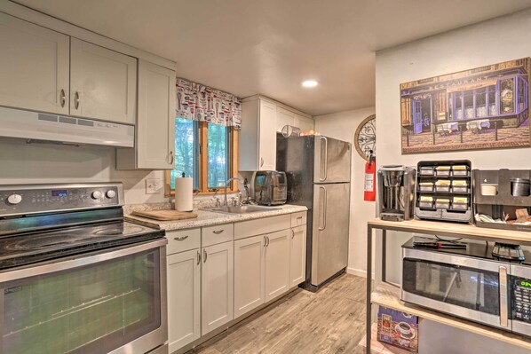 A kitchen with white cabinets, a stainless steel oven, a refrigerator, a coffee maker, and a microwave.
