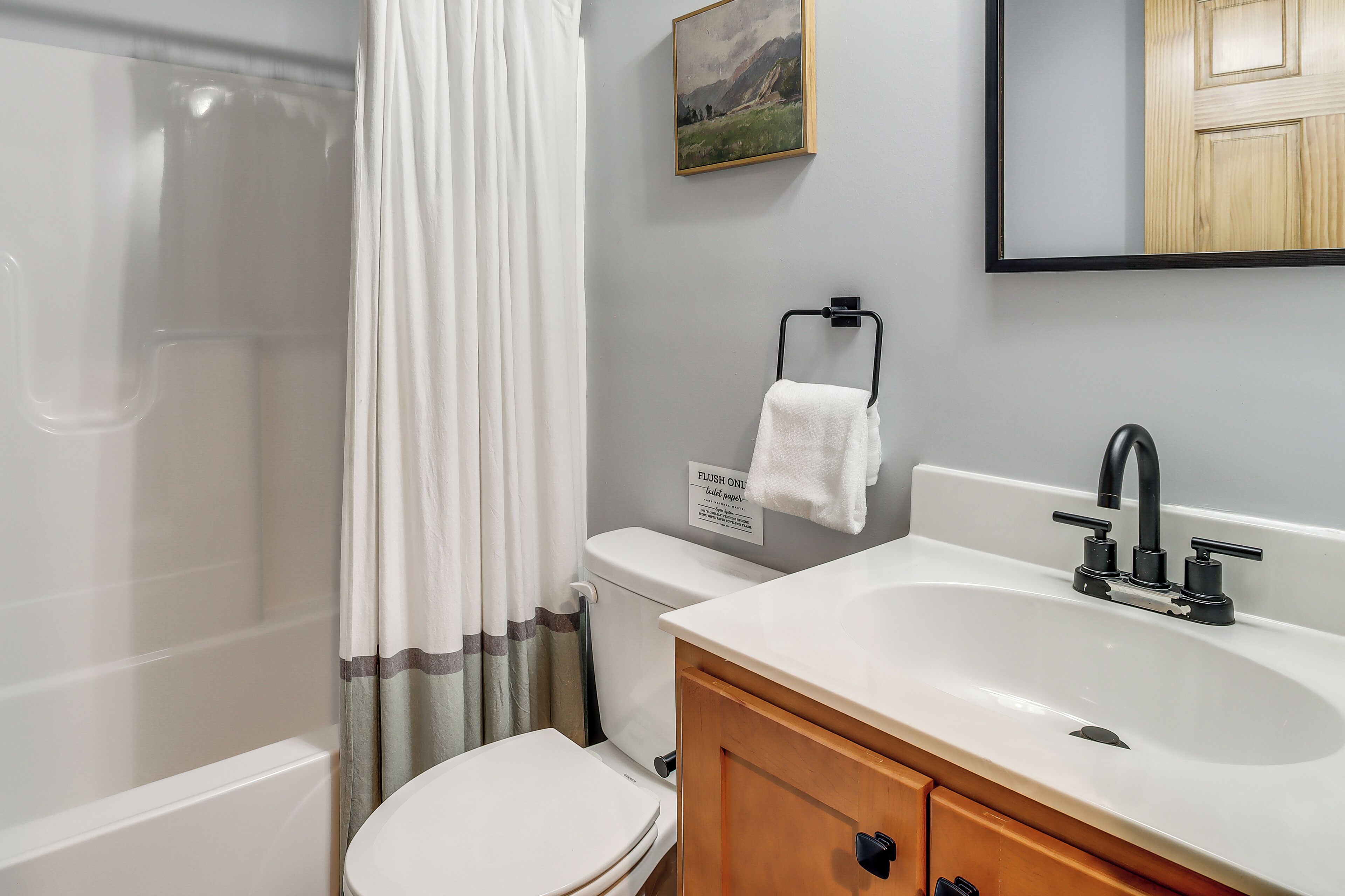 A bathroom with a shower, toilet, sink, and a towel rack.