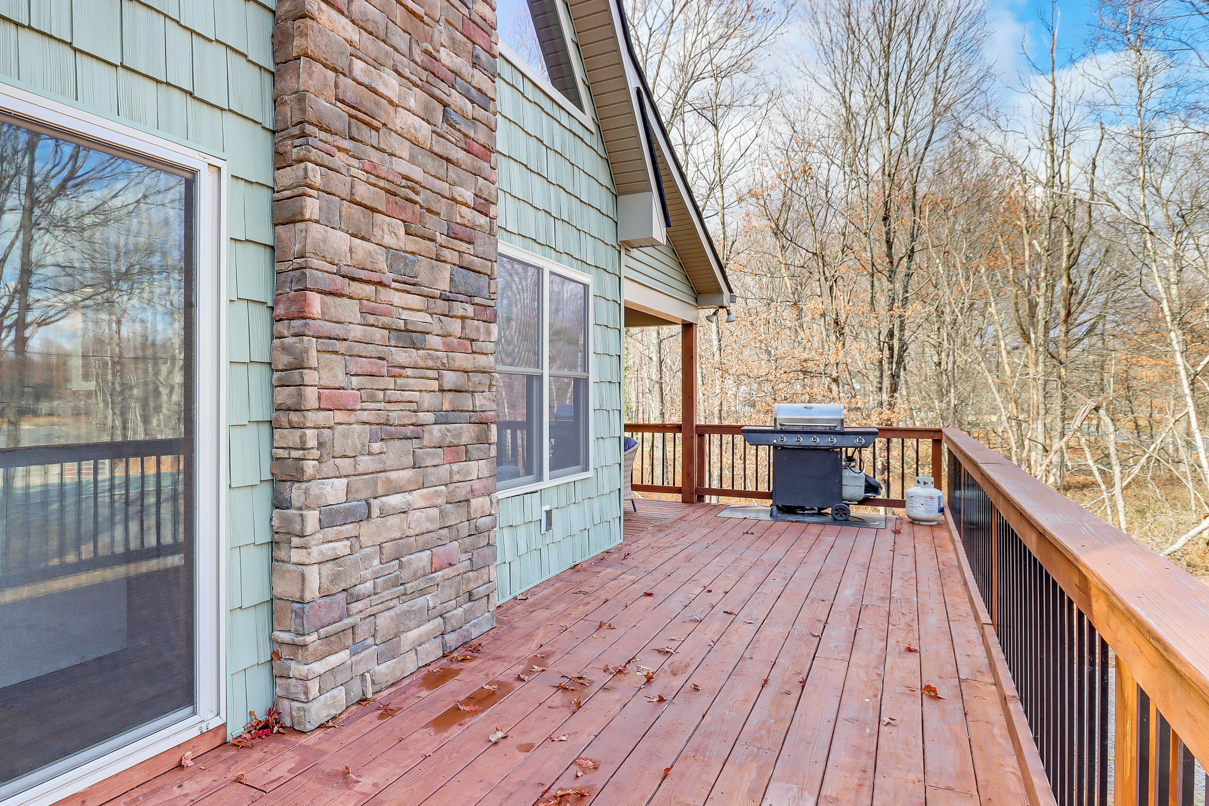 A wooden deck with a stone wall and a grill area.