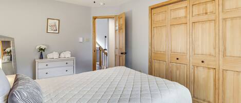 Un dormitorio con cama, cómoda, espejo, ventilador de techo y armario.