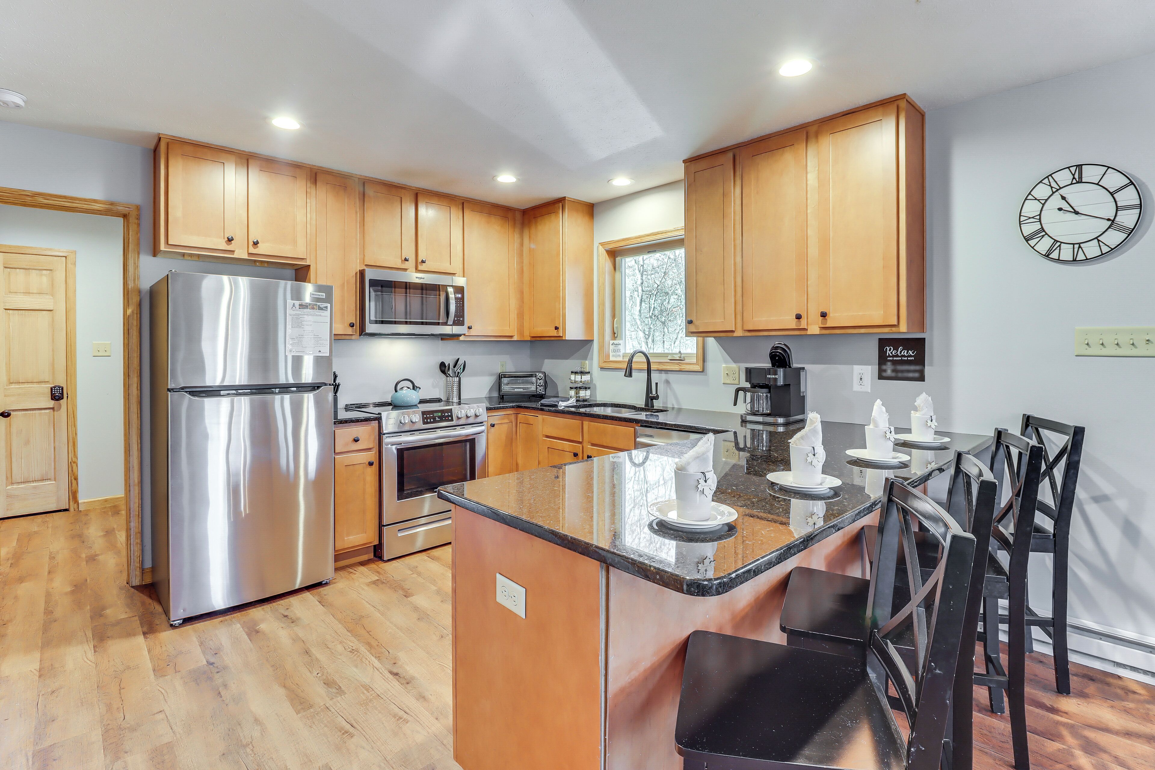 A modern kitchen with wooden cabinets, stainless steel appliances, and a central island with bar stools.