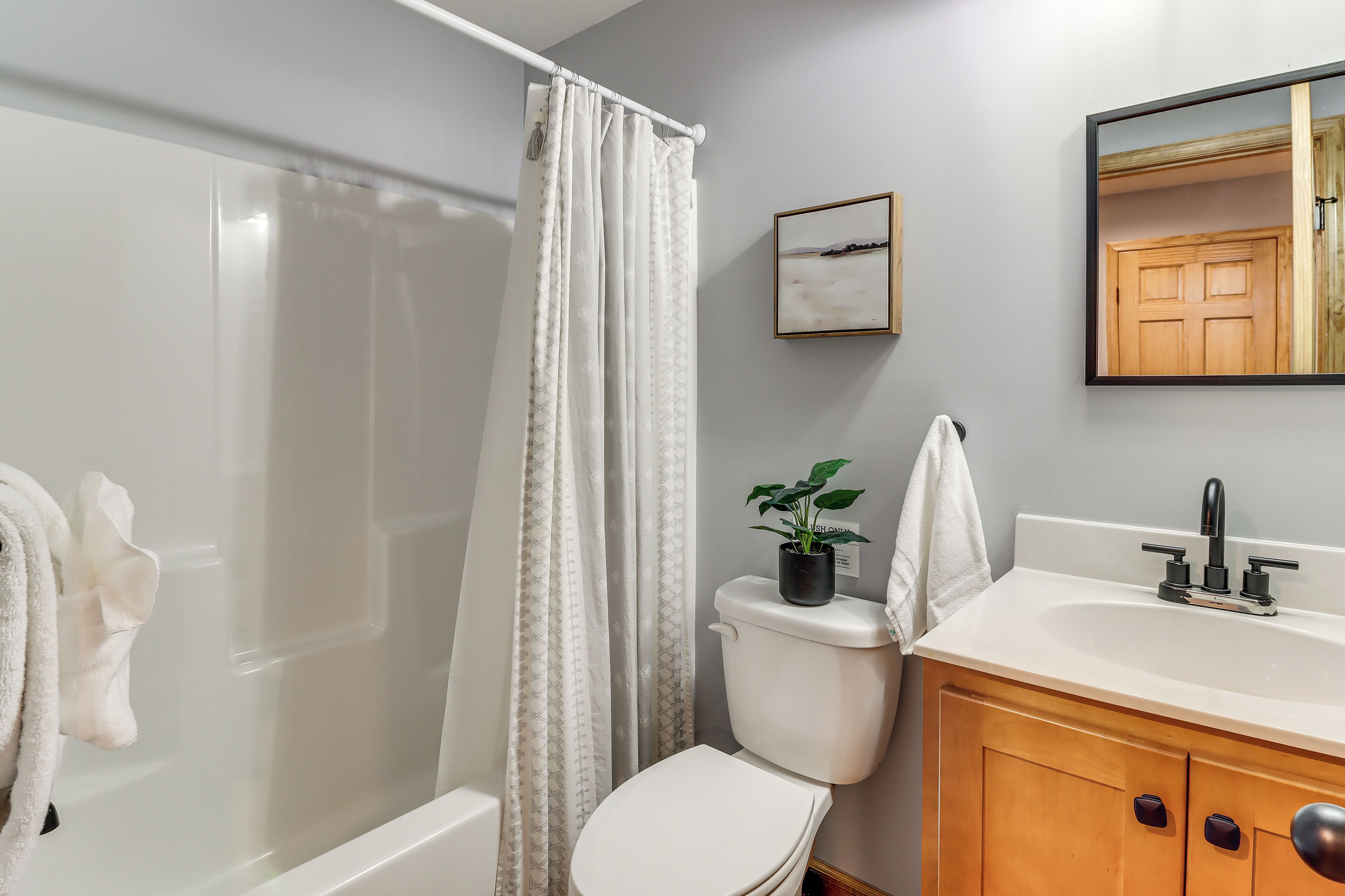 A bathroom with a shower, toilet, sink, and a mirror.