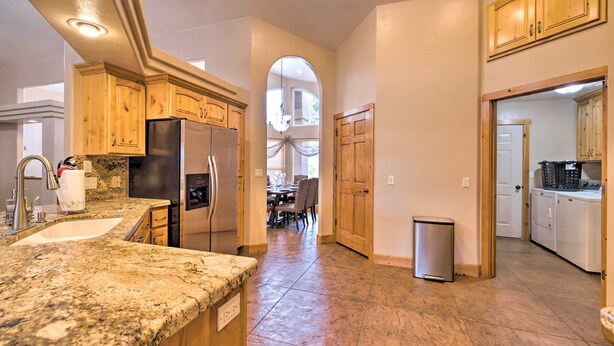 A kitchen with granite countertops, wooden cabinets, stainless steel appliances, and a tiled floor. - Hurricane Home w/ Pool & Spa ~ 25 Mi to Zion! (Hurricane)