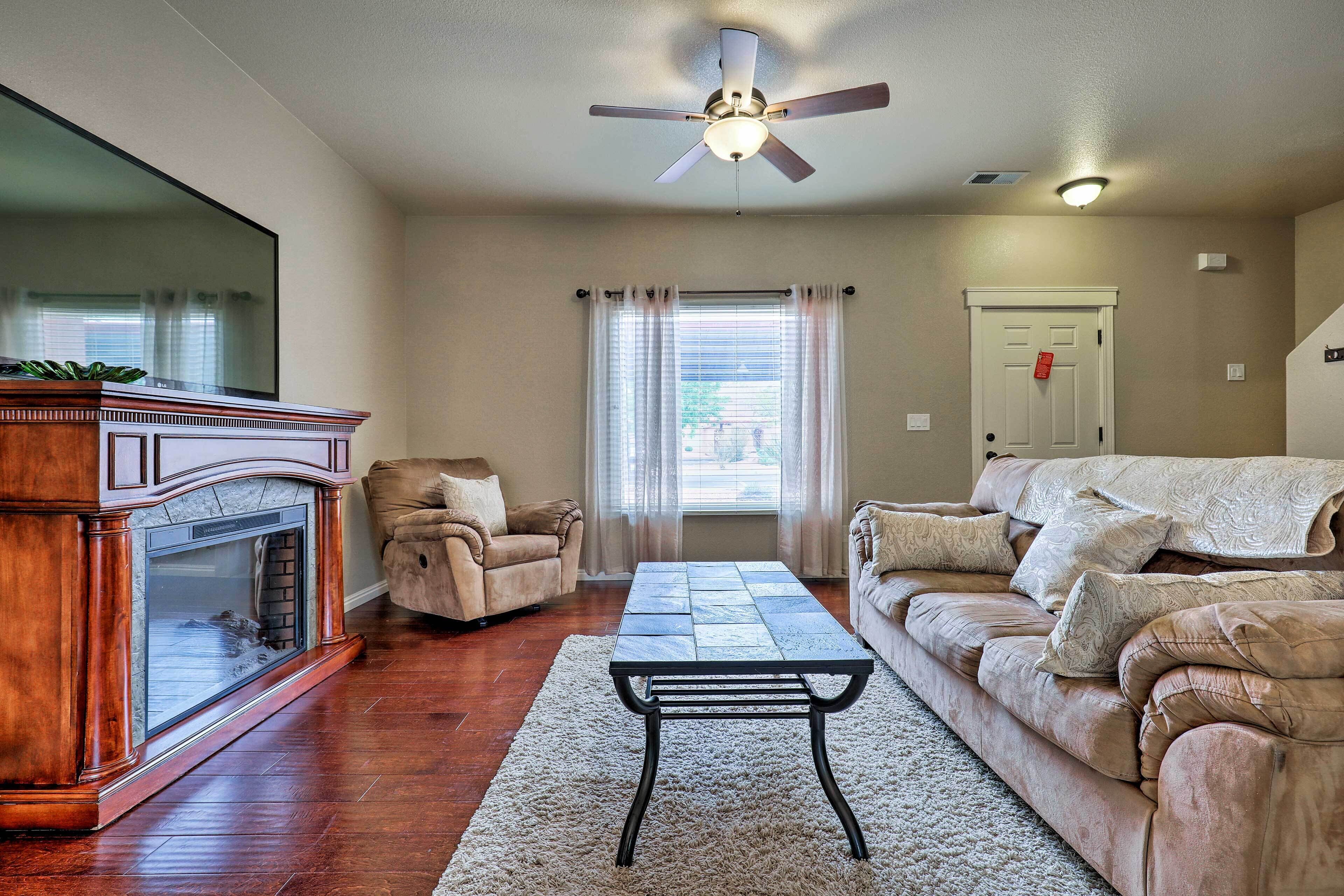 A living room with a fireplace, a sofa, a coffee table, and a ceiling fan.