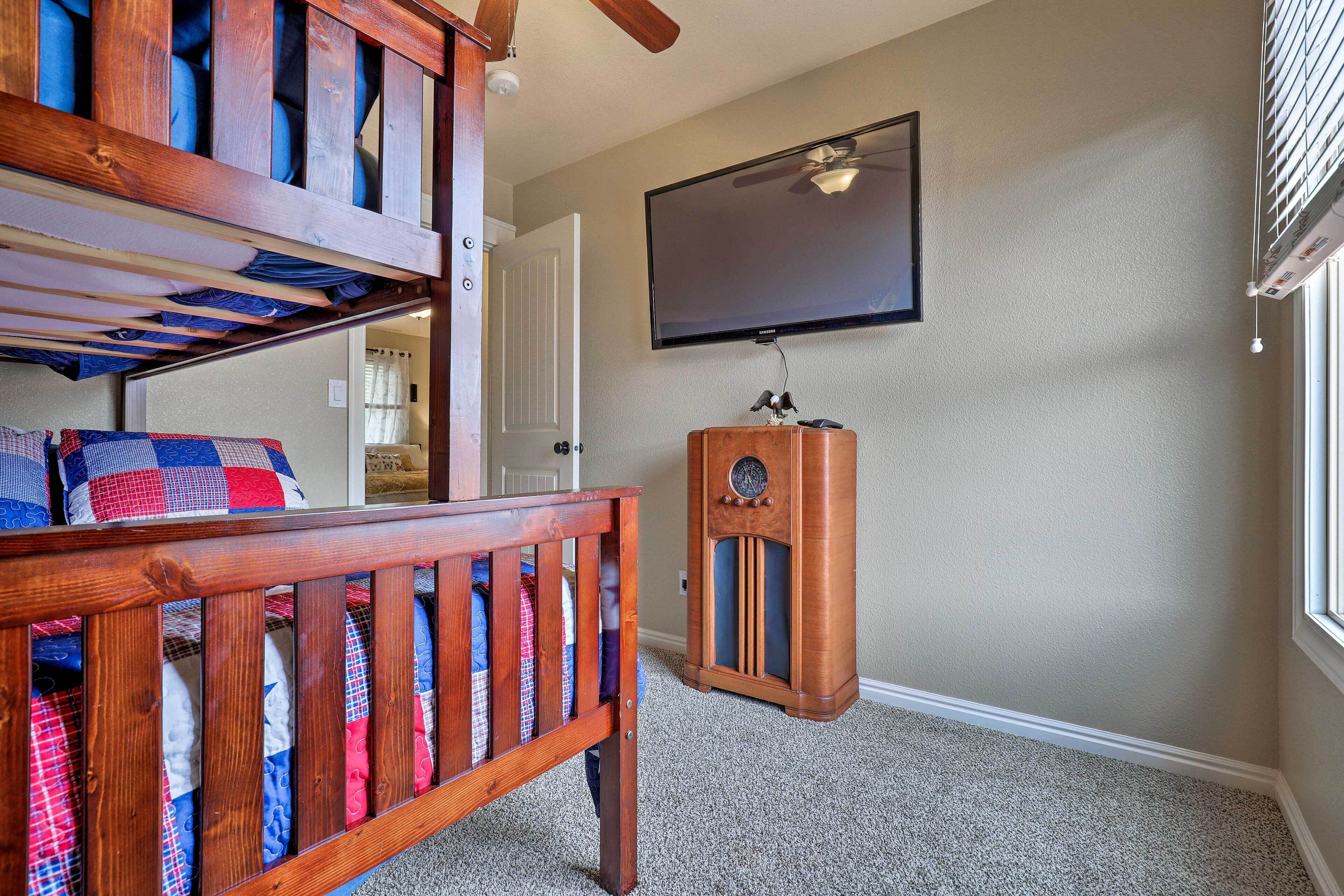 A room with a bunk bed, a television mounted on the wall, and a wooden cabinet.