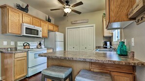 A kitchen with wooden cabinets, a white stove, a microwave, and a ceiling fan. - Lovely Kanab Condo in Dwtn, 30 mi to Zion NP! (Kanab)