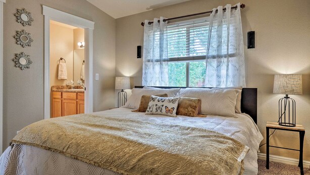 A bedroom with a large bed, two bedside lamps, a window with curtains, a nightstand, and a mirror. - Lovely Kanab Condo in Dwtn, 30 mi to Zion NP! (Kanab)