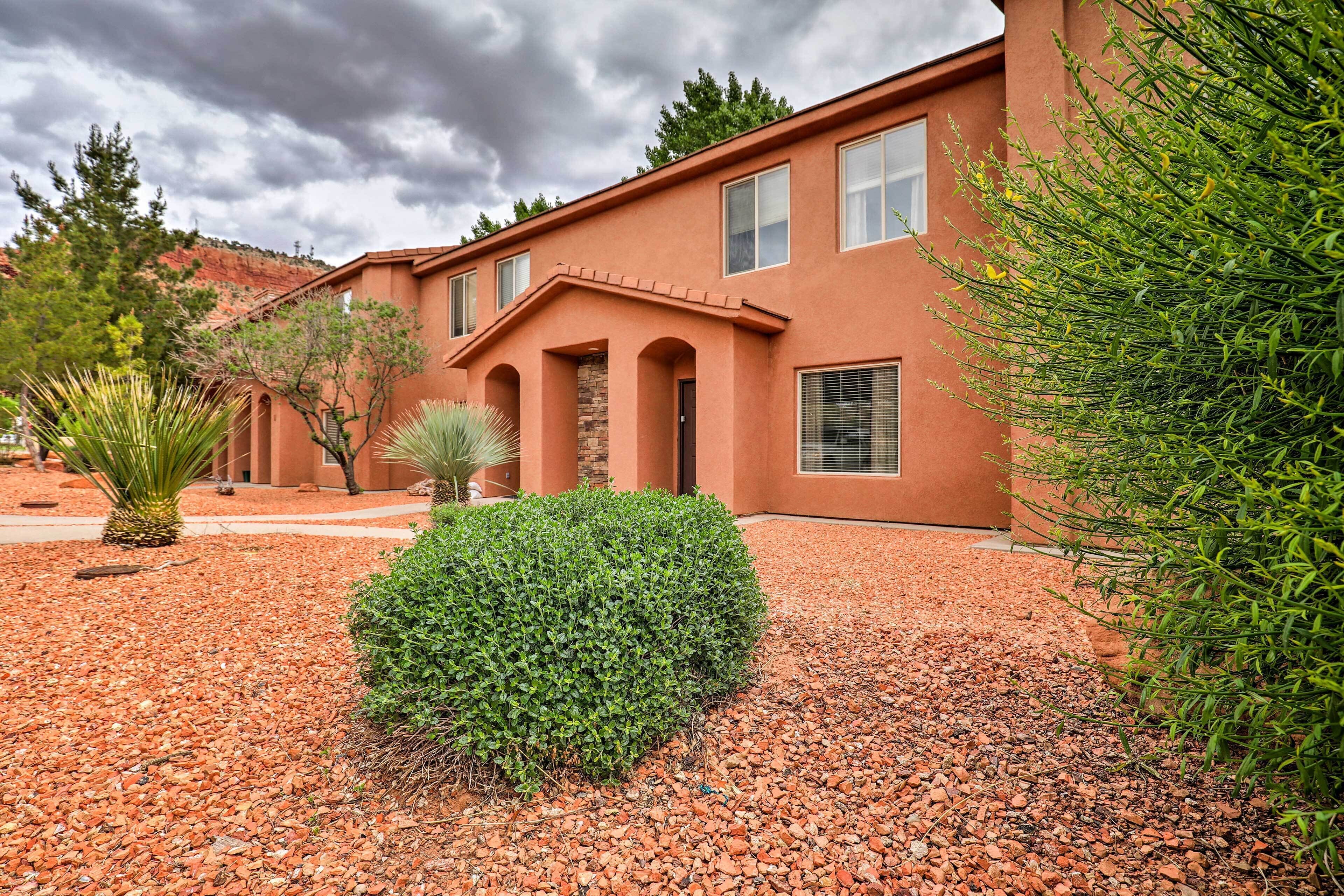 A building with a stucco exterior, arched doorways, and a gravel driveway.