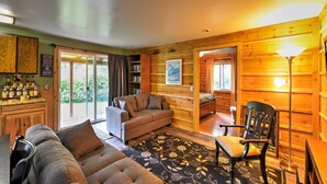 A cozy cabin interior with a sofa, a chair, a dining table, and a kitchen area with a bar. - Peaceful, Quiet Seward Apt W/back Yard & Mtn Views (Seward)