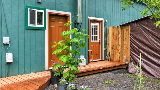 A green building with two doors, a wooden deck, and potted plants. - Peaceful, Quiet Seward Apt W/back Yard & Mtn Views (Seward)