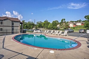A swimming pool with lounge chairs, a fenced area, and a building in the background. - Pool Access & Private Patio: Branson West Condo! (Branson West)