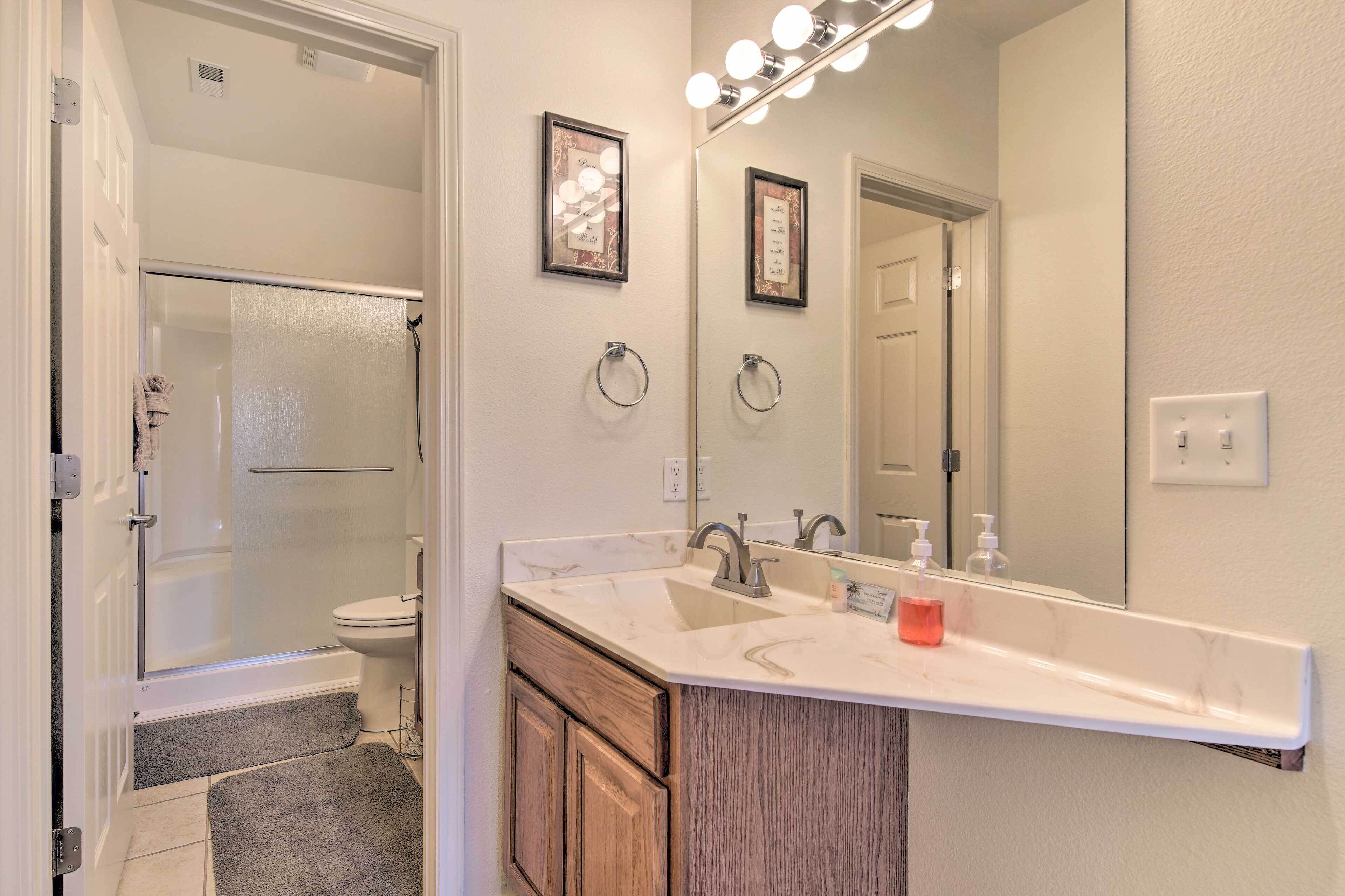 A bathroom with a large mirror, vanity, and a shower.