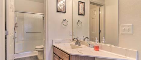 A bathroom with a large mirror, vanity, and a shower.