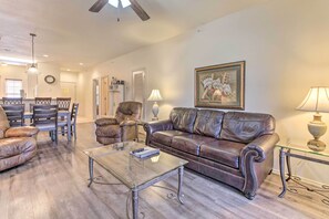 A living room with a brown leather sofa, a glass coffee table, and a dining area with chairs and a table. - Pool Access & Private Patio: Branson West Condo! (Branson West)