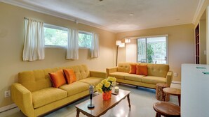 A living room with two yellow sofas, a wooden coffee table, and a vase with flowers. - Charming Mid-century House - Just Steps to Lake! (Lakeland)