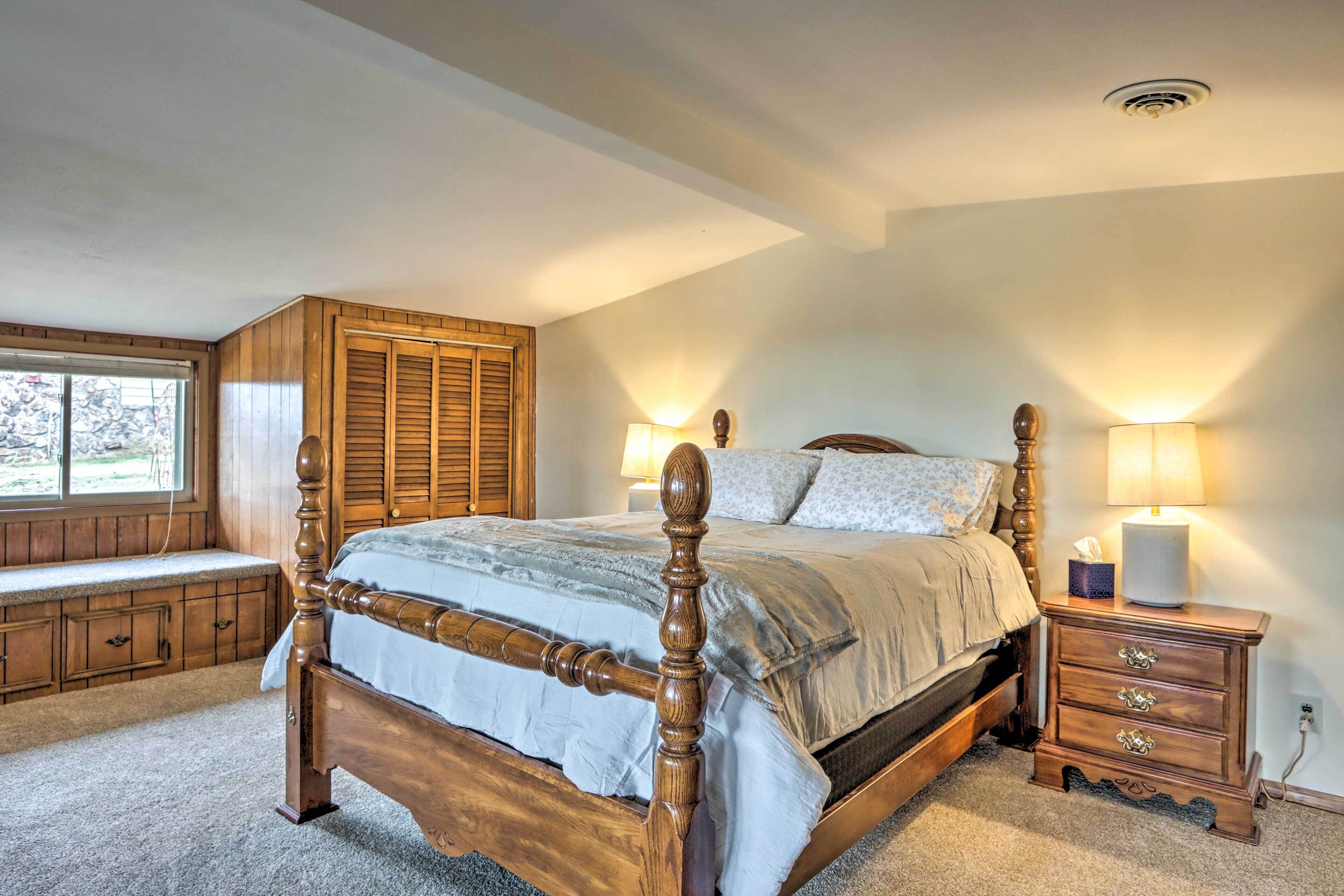 Een slaapkamer met een houten bed, een bankje bij het raam, een nachtkastje met een lamp en een wandradiator.