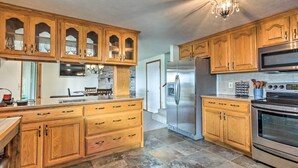 A kitchen with wooden cabinets, a stainless steel refrigerator, an oven, and a chandelier. - Lakeside Urbana Home - Near Hunting & Fishing! (Urbana)