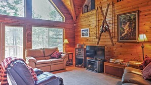 A cozy log cabin interior with a leather sofa, a television, and a fireplace. - Hot Tub, Deck & Trail Access: Shaver Lake Cabin (Shaver Lake)