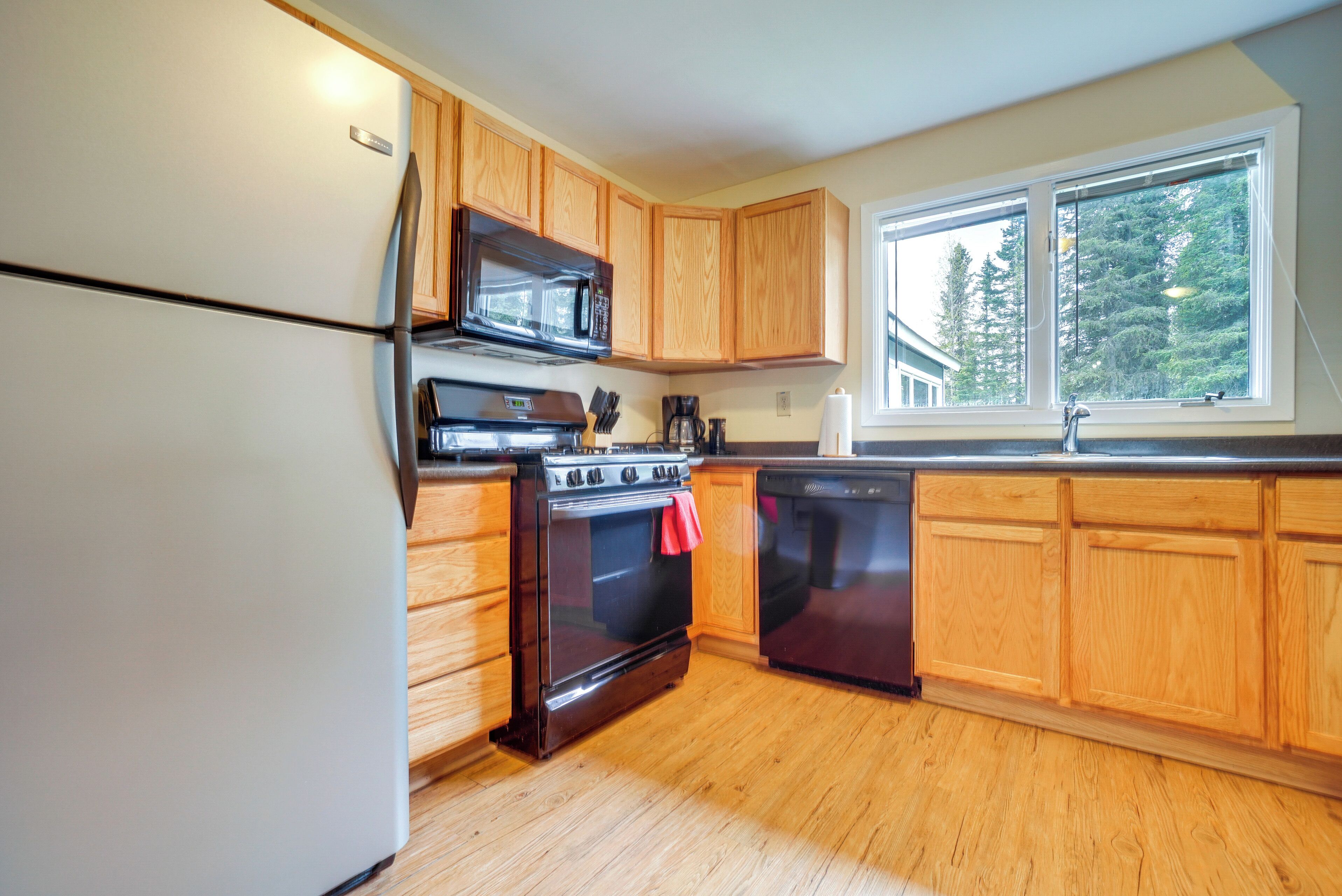 A kitchen with wooden cabinets, a stainless steel refrigerator, a microwave, a stove, and a dishwasher.