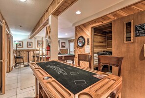 Une table de billard en bois se trouve dans une pièce aux murs et au plafond en bois, avec une horloge et des tableaux encadrés accrochés aux murs.