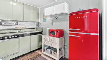Uma cozinha retrô com uma geladeira Galanz vermelha, um fogão antigo e um armário branco com uma placa com tema de vida.