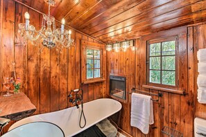 A wooden cabin bathroom with a freestanding bathtub, a chandelier, and two windows. - Hot Springs Studio ~ 3 Mi to National Park! (Hot Springs)