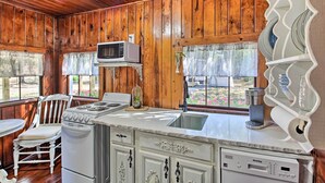 A kitchen with wooden walls, a white stove, a microwave, a sink, and a dishwasher. - Hot Springs Studio ~ 3 Mi to National Park! (Hot Springs)