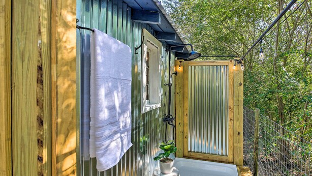 A wooden cabin with a built-in hot tub, a towel hanging on the door, and a potted plant on a stool. - Hot Springs Studio ~ 3 Mi to National Park! (Hot Springs)