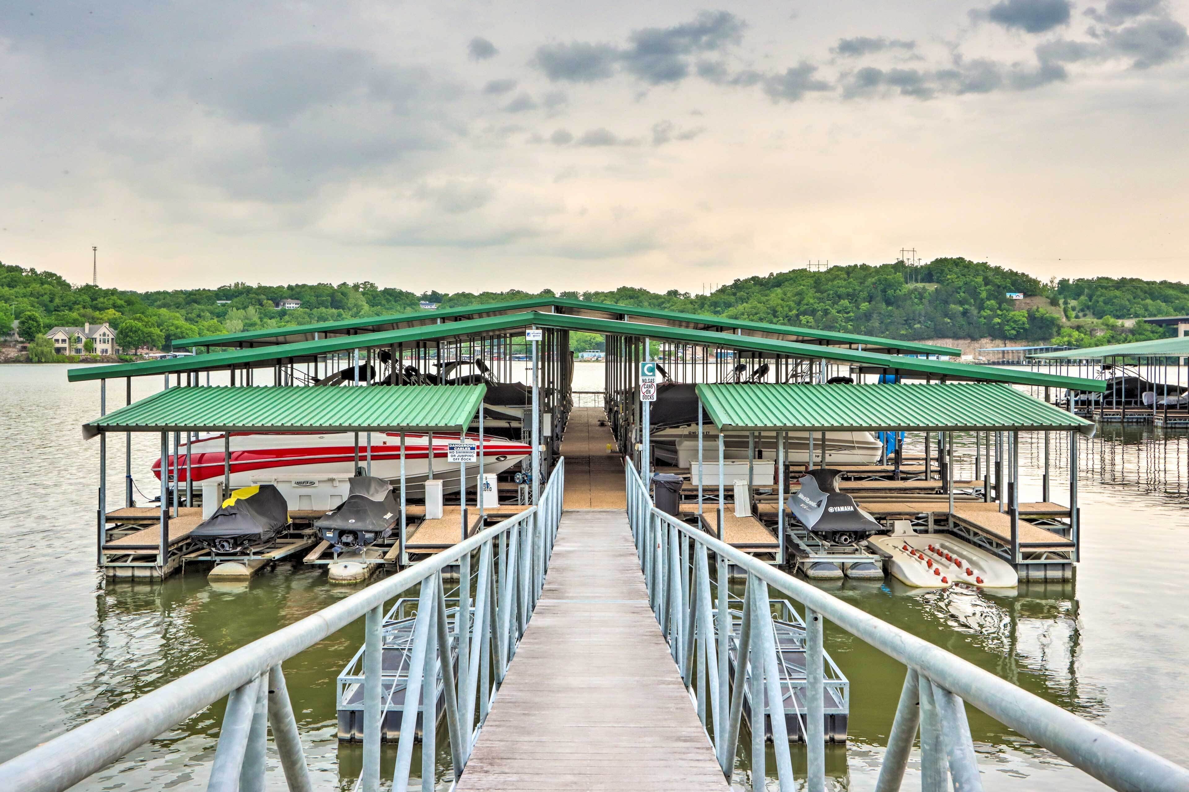 A pier leading to a boat dock with covered seating areas and boats.