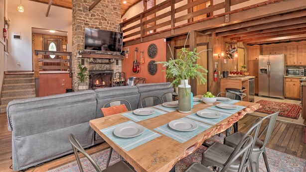 Un intérieur chaleureux et rustique, avec une cheminée en pierre, des poutres apparentes, un coin repas avec une table en bois pouvant accueillir six personnes, et une cuisine équipée d’appareils modernes.