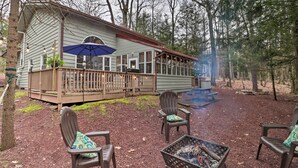 Une cabane dotée d’une terrasse, de meubles de jardin et d’un foyer extérieur.