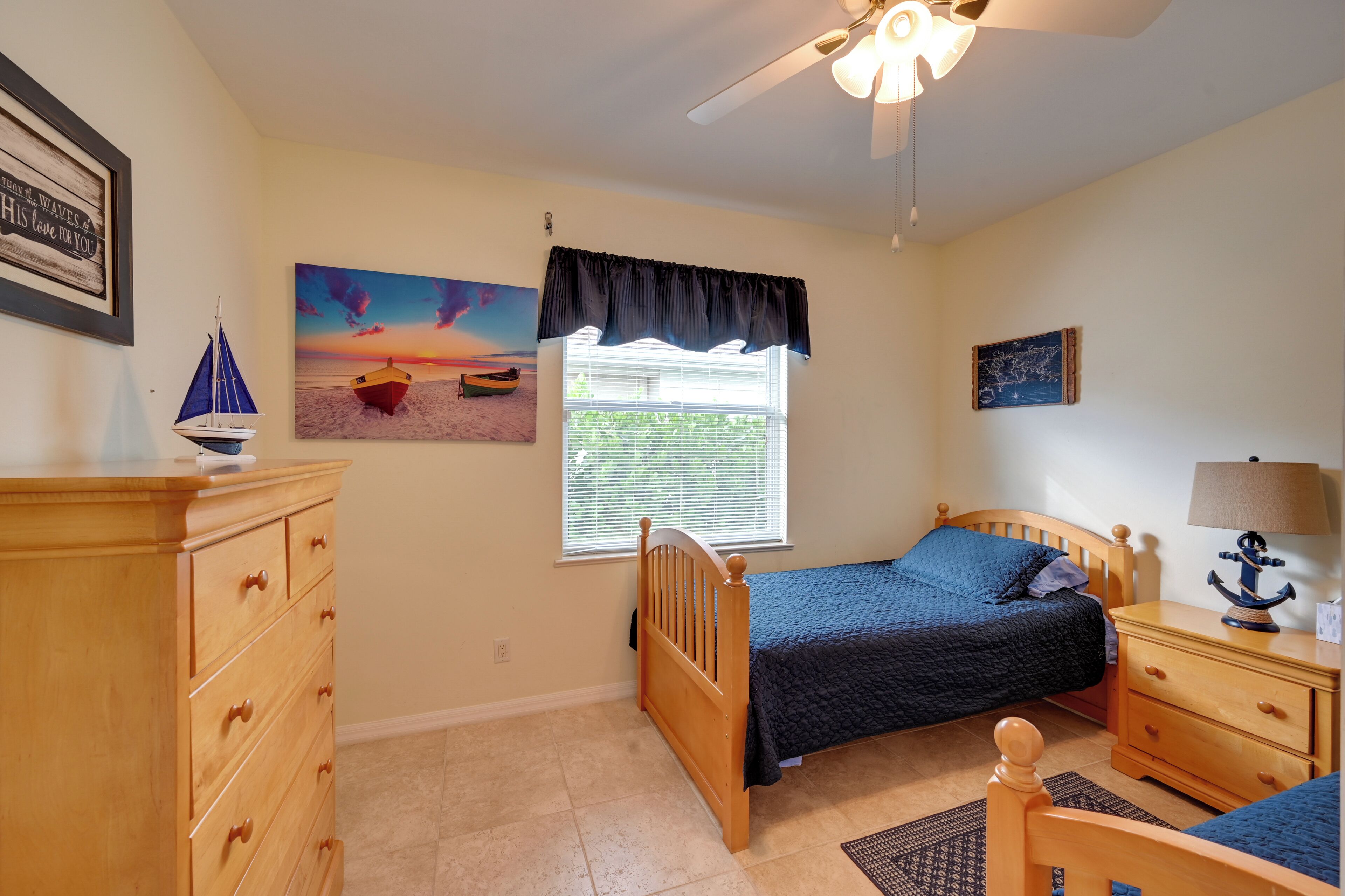A bedroom with a bed, dresser, nightstand, and a ceiling fan.