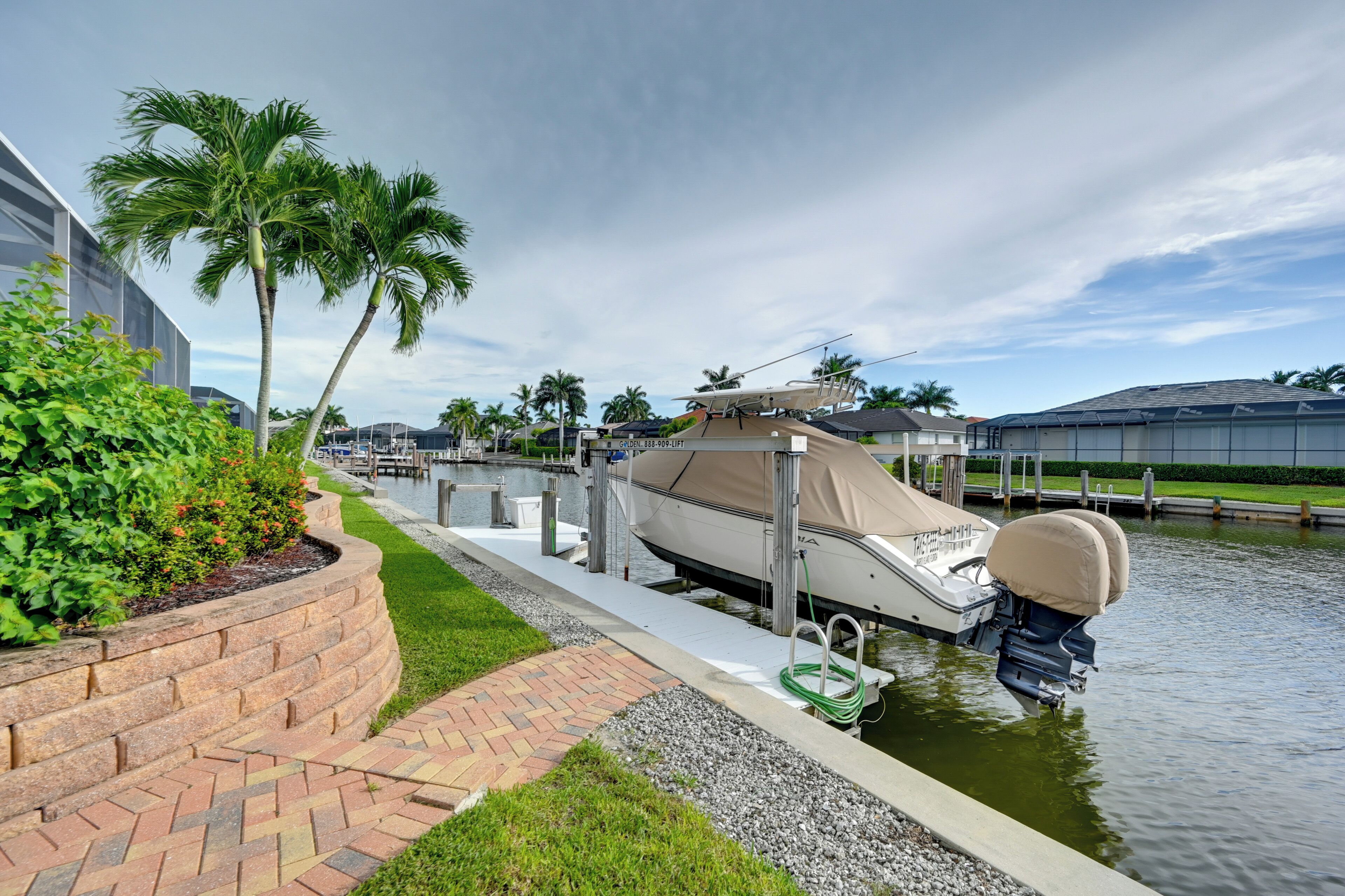 A marina with a boat docked, palm trees, and a clear sky.