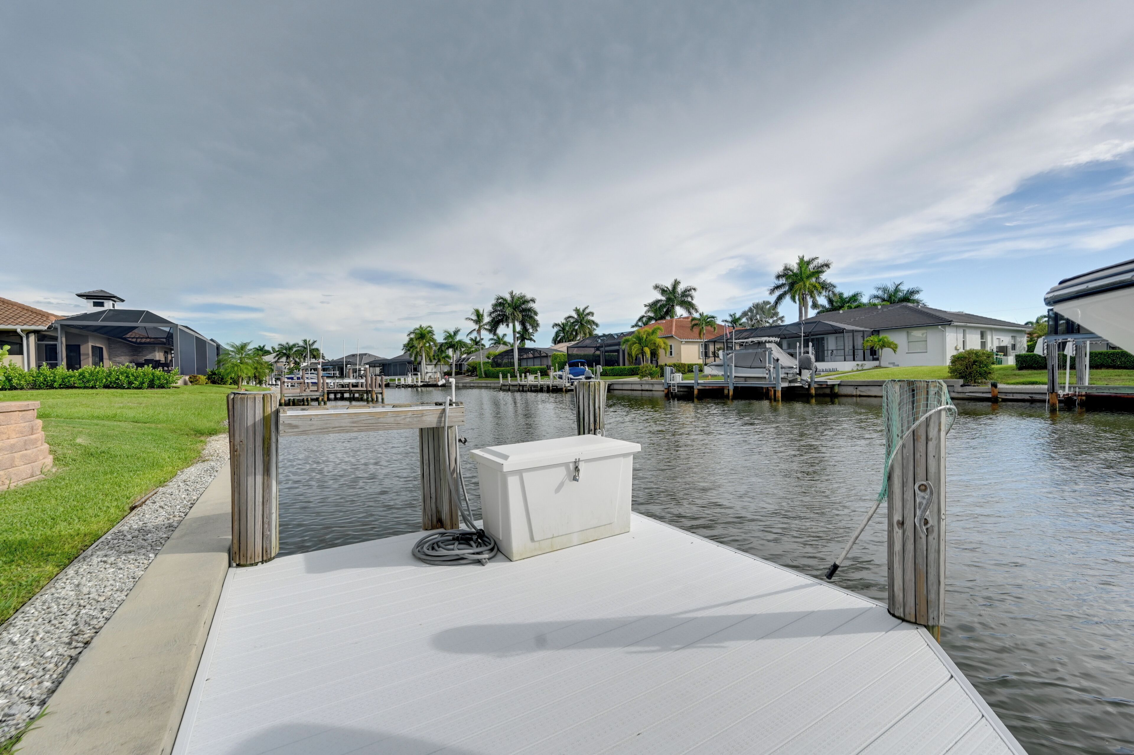 A waterfront dock with a white storage box, a rope, and a wooden post.