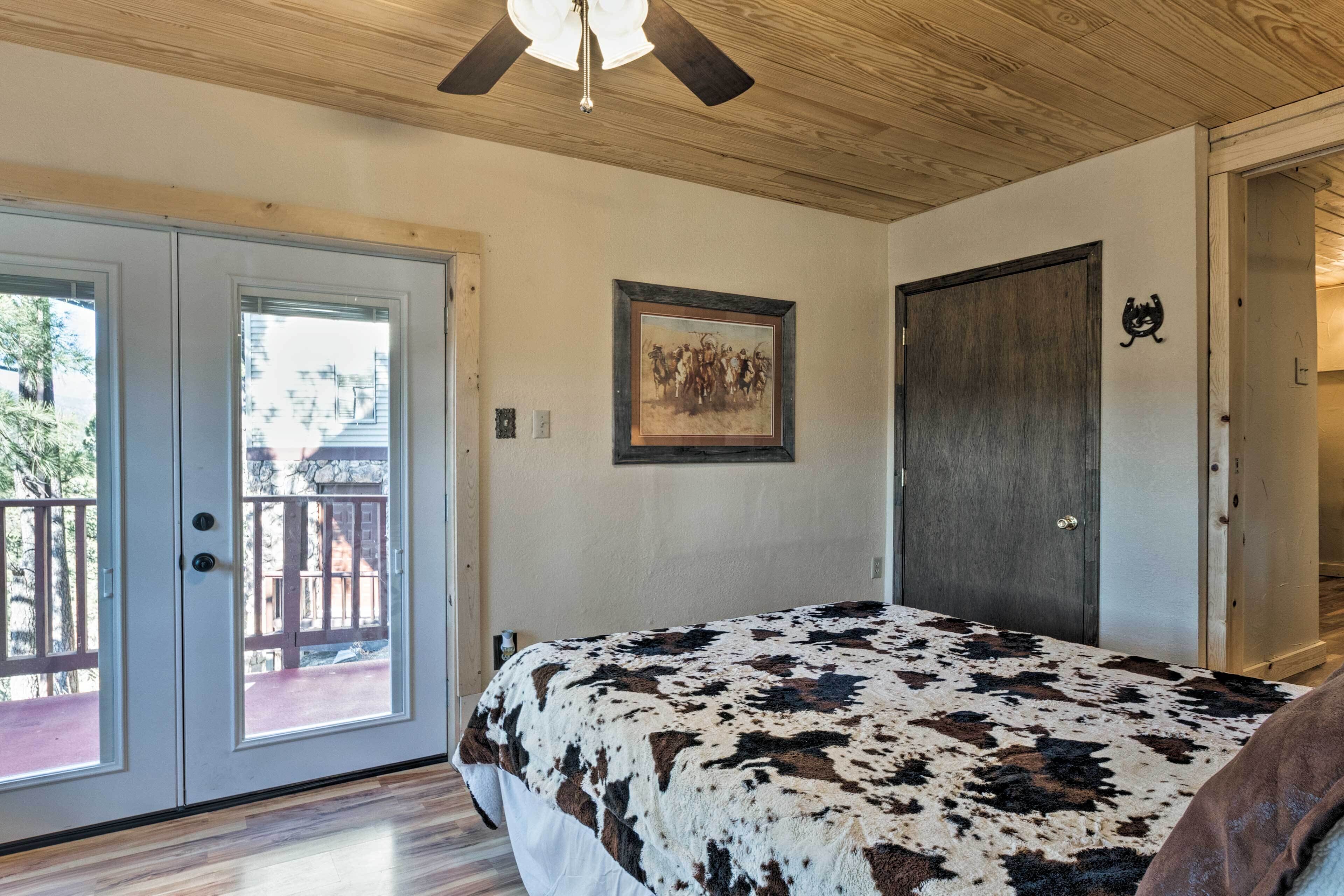 A bedroom with a bed, a ceiling fan, a door, and a balcony.