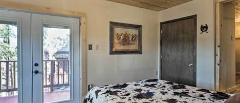 A bedroom with a bed, a ceiling fan, a door, and a balcony.