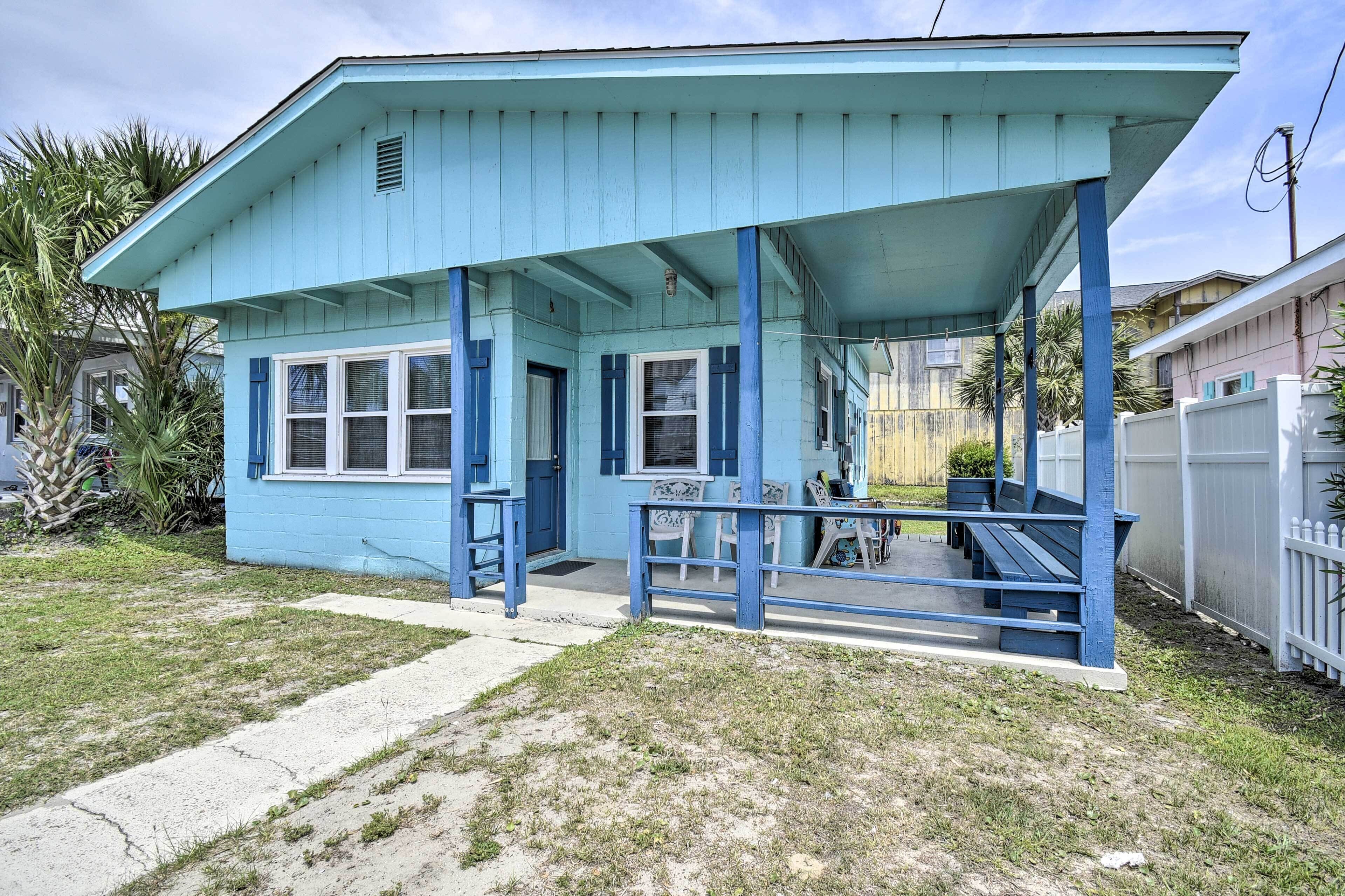 A small, single-story house with a blue exterior and a covered porch.