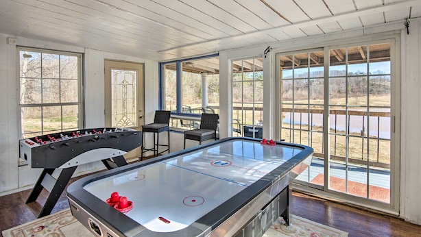 A room with a pool table, a foosball table, and large windows offering a view of the outdoors. - Game Room & Views: Lakefront Shelby Home! (Shelby)