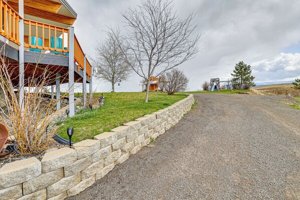A two-story house with a stone retaining wall and a gravel driveway.