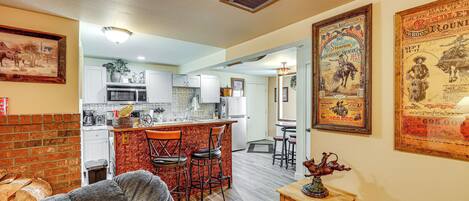 A spacious living area with a fireplace, a kitchen with white cabinets, and a dining area with a bar.
