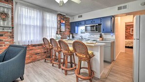 A modern kitchen with blue cabinets, a central island, and a dining area with wicker chairs. - Ground Floor Unit: 10 Miles to Myrtle Beach (Murrells Inlet)
