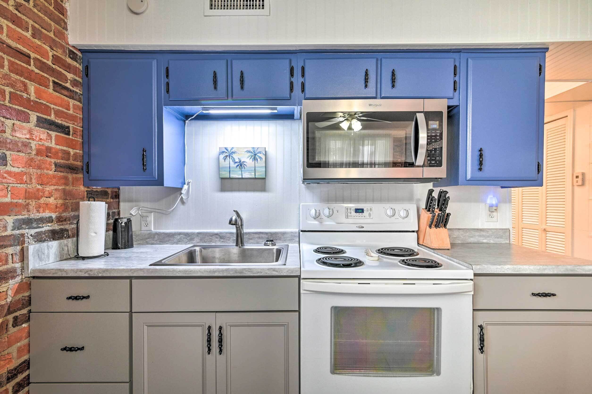 Une cuisine avec des armoires bleues, une cuisinière blanche et un four à micro-ondes.