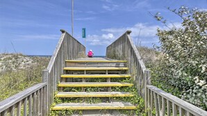 A wooden staircase leading to a beach with a sign indicating 'Sturbridge' in the distance. - Home w/ Deck in Corolla Light: Walk to Beach! (Corolla)