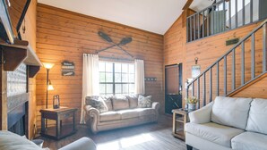 Ein gemütliches Blockhaus-Interieur mit Holzausstattung, einer Couch, einem Tisch und einer Treppe.