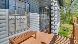 Eine hölzerne Bank auf einer Veranda mit Glastür und -fenstern.