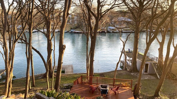 A wooden deck with outdoor furniture, a fire pit, and a view of a lake with boats. - 10 Mi to New Braunfels: Waterfront Seguin Gem (Seguin)